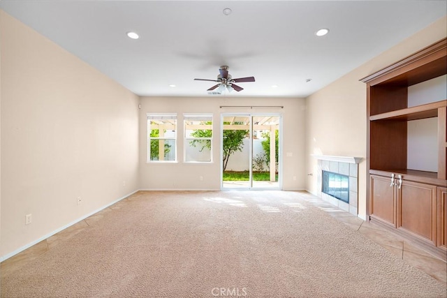 unfurnished living room with ceiling fan, light colored carpet, and a fireplace