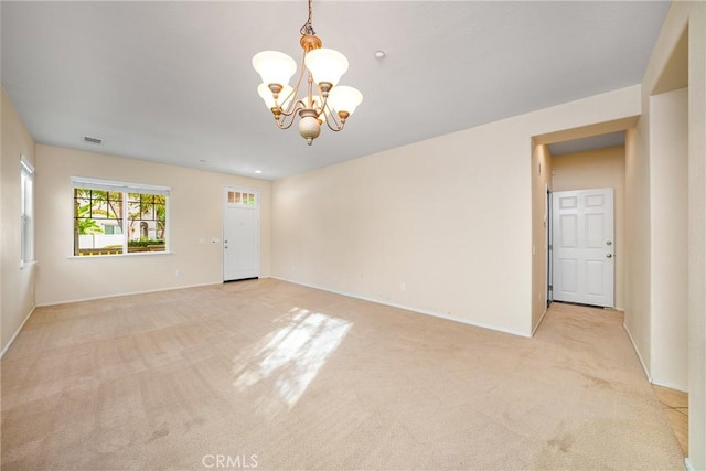 carpeted spare room featuring a notable chandelier