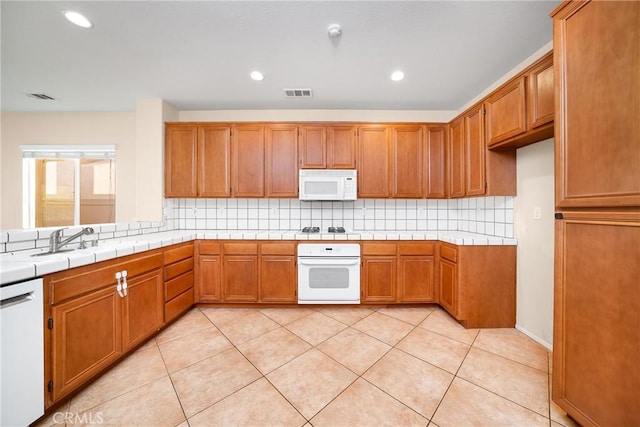 kitchen with tile countertops, backsplash, light tile patterned flooring, and white appliances