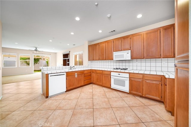 kitchen featuring kitchen peninsula, ceiling fan, backsplash, white appliances, and sink