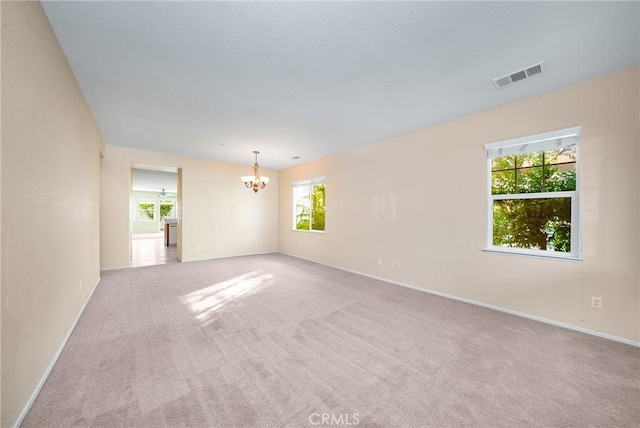 carpeted empty room with a chandelier