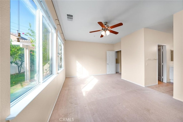 empty room featuring ceiling fan, a healthy amount of sunlight, and light colored carpet