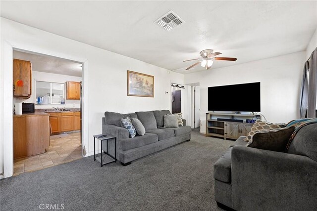 living room featuring light carpet, ceiling fan, and sink