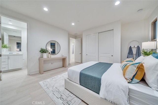 bedroom with a closet, ensuite bath, and light wood-type flooring