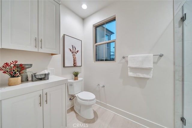 bathroom with a shower with door, hardwood / wood-style floors, toilet, and vanity