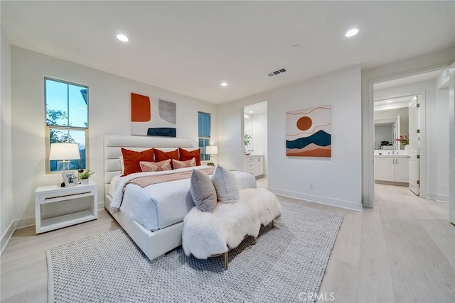 bedroom with connected bathroom and light hardwood / wood-style flooring