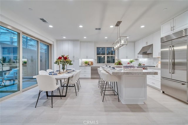 kitchen with white cabinetry, a kitchen island, stainless steel appliances, and pendant lighting