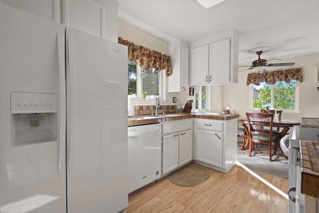 kitchen with sink, white appliances, white cabinets, and light wood-type flooring