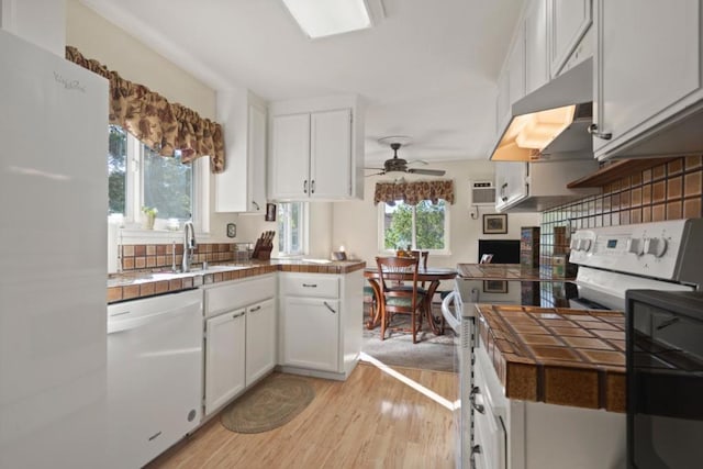 kitchen featuring white appliances, light hardwood / wood-style flooring, white cabinetry, tile countertops, and kitchen peninsula