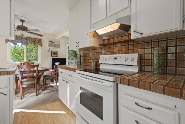 kitchen with light hardwood / wood-style flooring, white range with electric stovetop, tasteful backsplash, a wall mounted air conditioner, and white cabinets