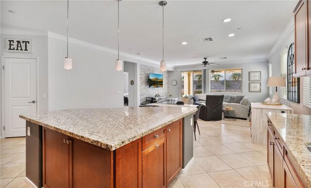 kitchen featuring light tile patterned floors, ceiling fan, hanging light fixtures, ornamental molding, and light stone counters