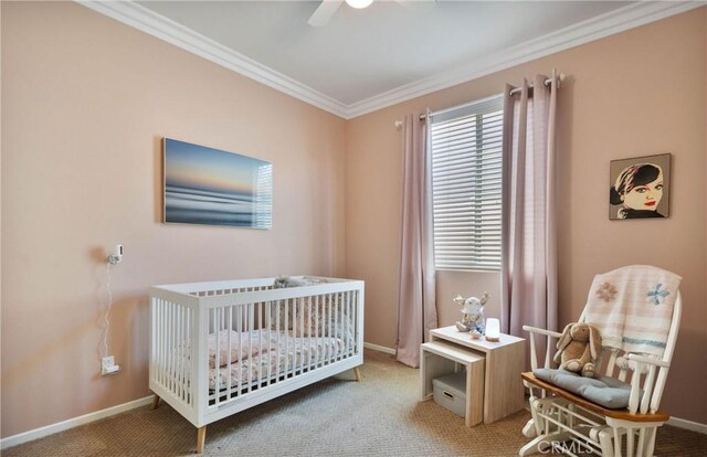 bedroom featuring ceiling fan, a nursery area, ornamental molding, and carpet flooring