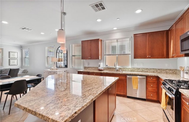 kitchen featuring a center island, decorative light fixtures, stainless steel appliances, sink, and light stone counters