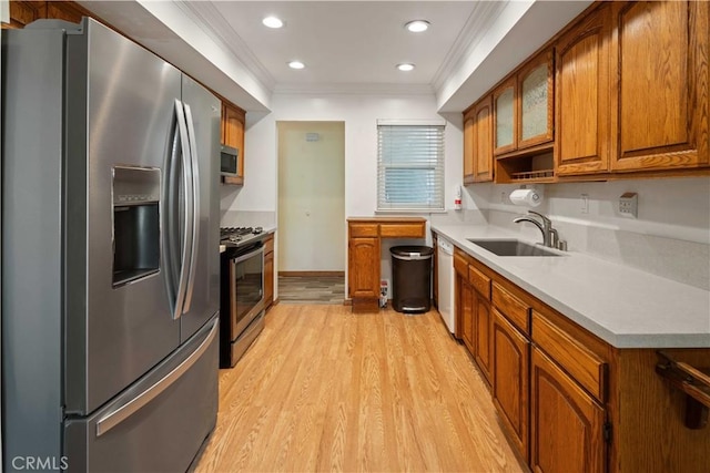 kitchen featuring light wood-type flooring, stainless steel appliances, ornamental molding, and sink