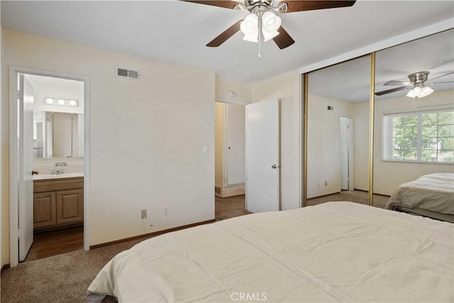 bedroom with ceiling fan, carpet, sink, connected bathroom, and a closet