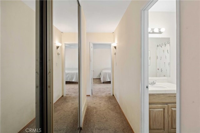 corridor with light colored carpet and sink