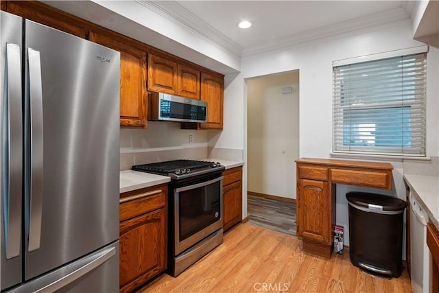 kitchen featuring ornamental molding, light hardwood / wood-style flooring, and stainless steel appliances