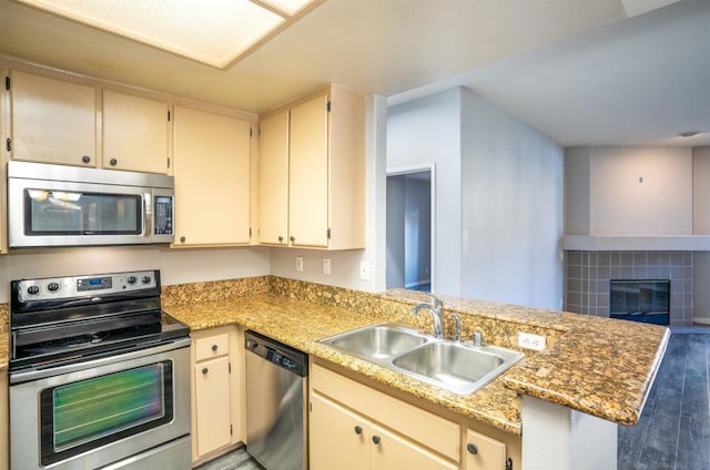 kitchen with sink, appliances with stainless steel finishes, kitchen peninsula, and cream cabinets