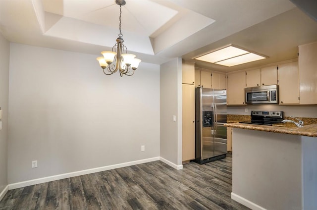 kitchen with cream cabinetry, stainless steel appliances, a raised ceiling, a chandelier, and pendant lighting