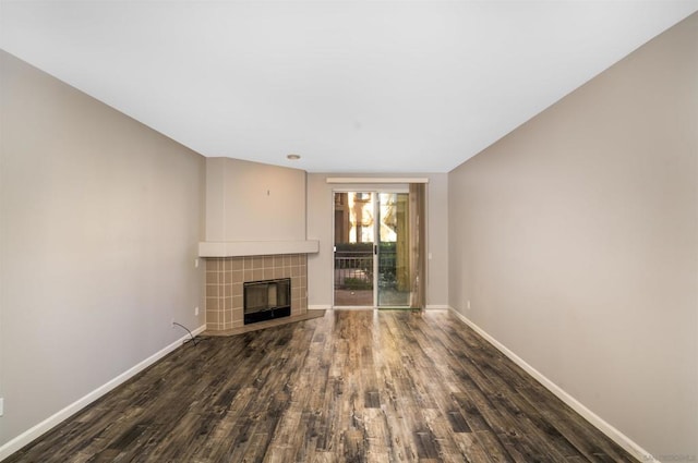 unfurnished living room with a tiled fireplace and dark hardwood / wood-style flooring