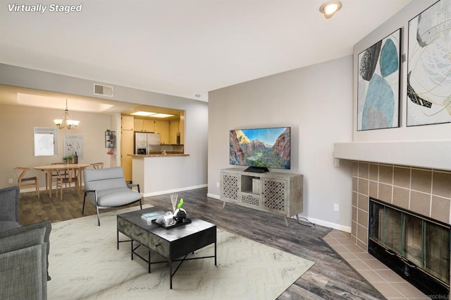 living room with a fireplace, an inviting chandelier, and hardwood / wood-style flooring