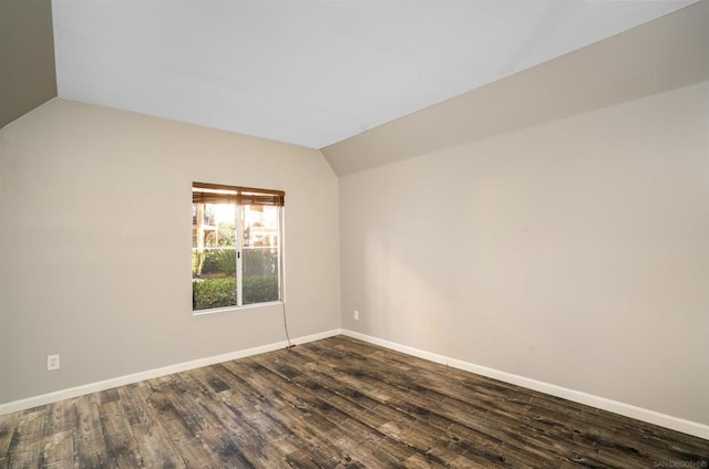 unfurnished room with vaulted ceiling and dark wood-type flooring