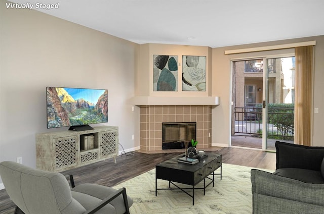 living room with wood-type flooring and a tiled fireplace