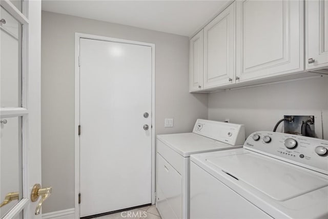 washroom with light tile patterned floors, washing machine and clothes dryer, and cabinets