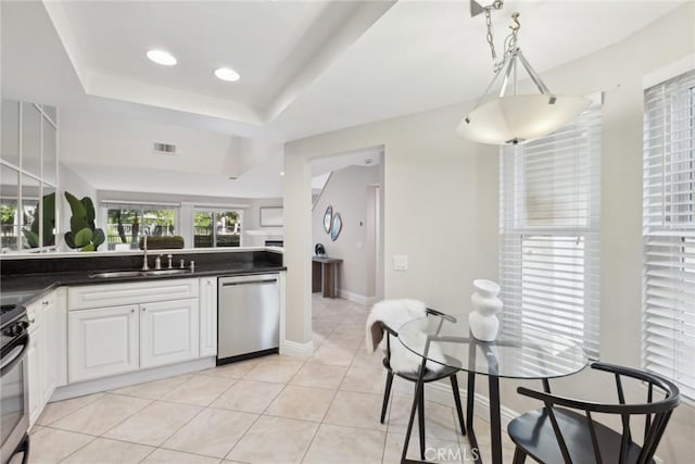 kitchen with pendant lighting, white cabinets, sink, a raised ceiling, and stainless steel dishwasher