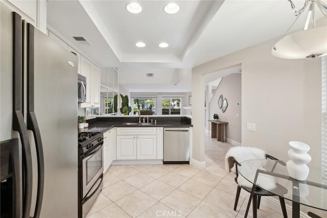 kitchen featuring stainless steel appliances, a raised ceiling, white cabinetry, and sink