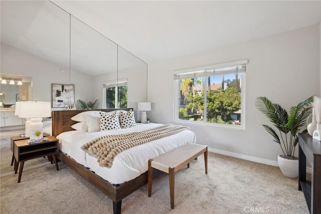 bedroom featuring vaulted ceiling, ensuite bathroom, and light carpet