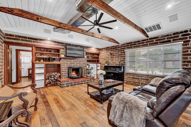 living room with ceiling fan, a brick fireplace, hardwood / wood-style flooring, built in features, and brick wall