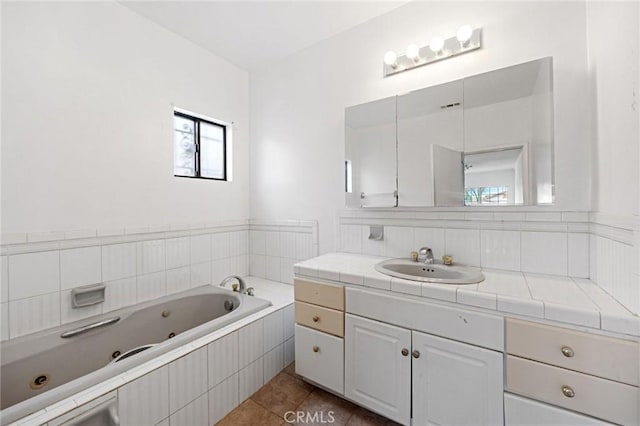 bathroom with tile patterned flooring, tiled tub, and vanity