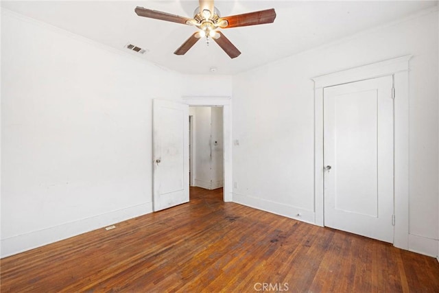 empty room with ceiling fan, dark hardwood / wood-style flooring, and ornamental molding