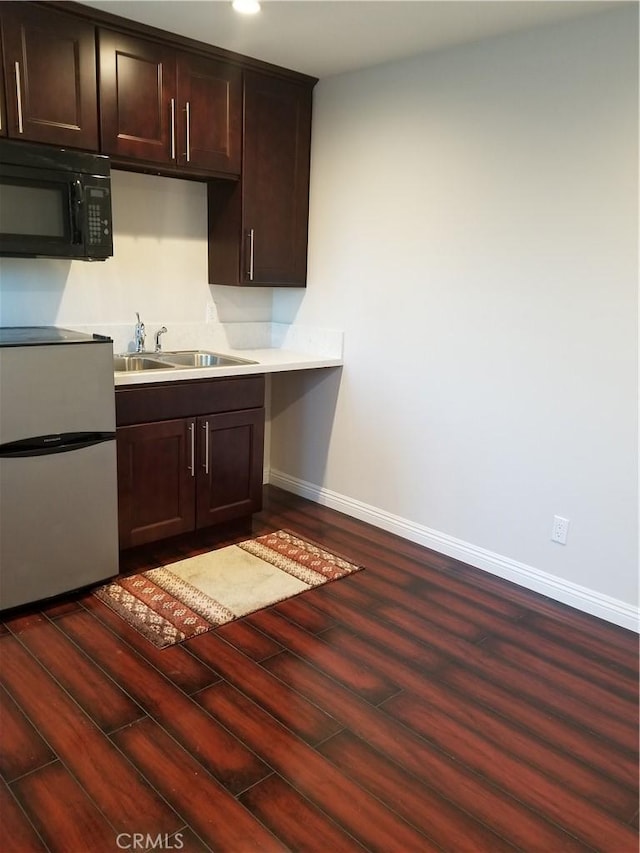 kitchen featuring dark brown cabinets, refrigerator, sink, and dark wood-type flooring