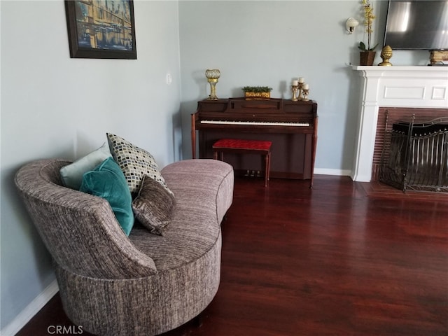 living area featuring dark wood-type flooring and a brick fireplace