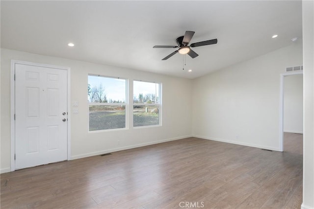 spare room with ceiling fan, light wood-type flooring, and vaulted ceiling