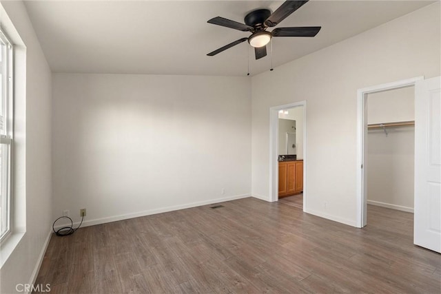 unfurnished bedroom featuring a spacious closet, ensuite bathroom, ceiling fan, a closet, and dark hardwood / wood-style flooring