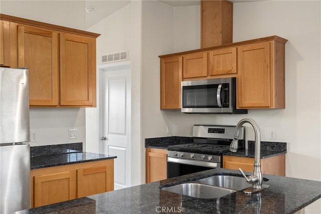 kitchen featuring sink, vaulted ceiling, stainless steel appliances, and dark stone countertops