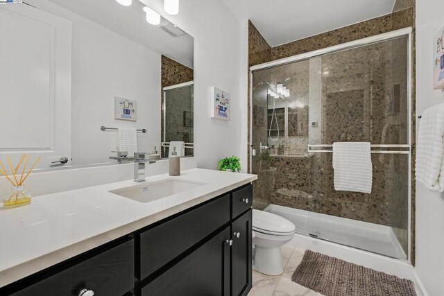 bathroom featuring toilet, vanity, and a shower with door