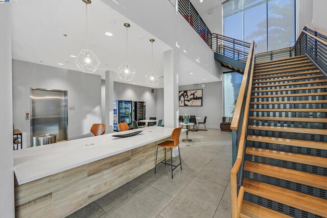 interior space featuring a kitchen bar, a towering ceiling, and pendant lighting