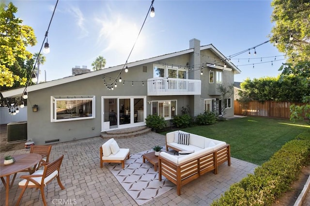 rear view of house with a balcony, a lawn, an outdoor hangout area, and a patio