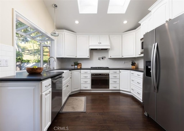 kitchen with hanging light fixtures, a skylight, appliances with stainless steel finishes, and white cabinetry