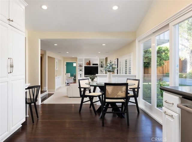 dining space featuring vaulted ceiling, built in features, and dark hardwood / wood-style floors