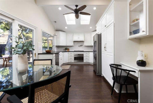 kitchen featuring pendant lighting, white cabinets, appliances with stainless steel finishes, ceiling fan, and lofted ceiling with skylight