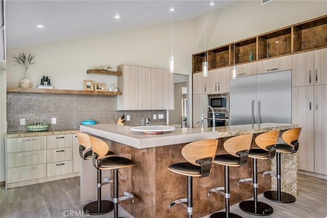 kitchen with a kitchen bar, a center island, built in appliances, and tasteful backsplash