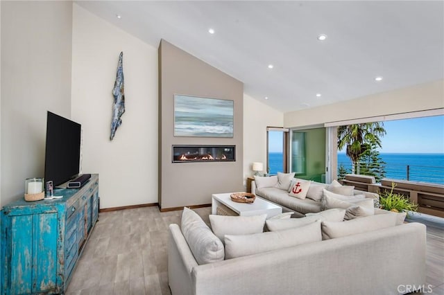 living room with a water view, light wood-type flooring, vaulted ceiling, and a wealth of natural light