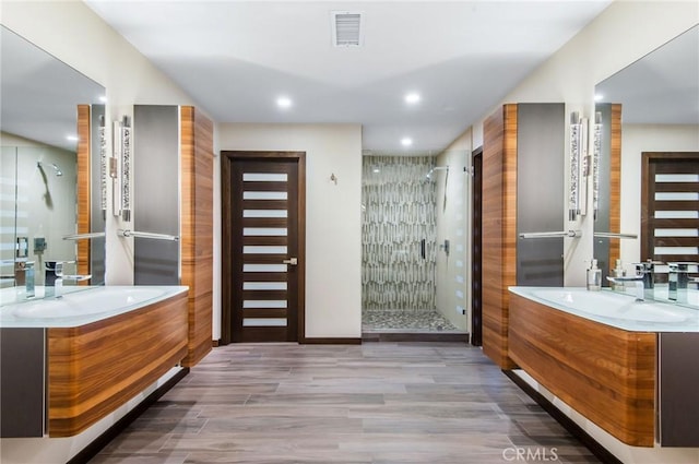 bathroom with vanity, hardwood / wood-style flooring, and a shower with door