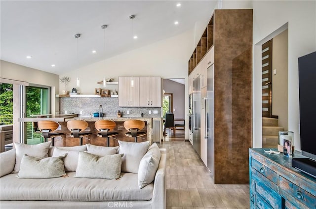 living room featuring a healthy amount of sunlight, lofted ceiling, light hardwood / wood-style flooring, and sink