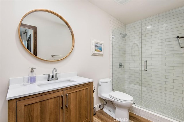 bathroom featuring toilet, vanity, a shower with door, and hardwood / wood-style floors